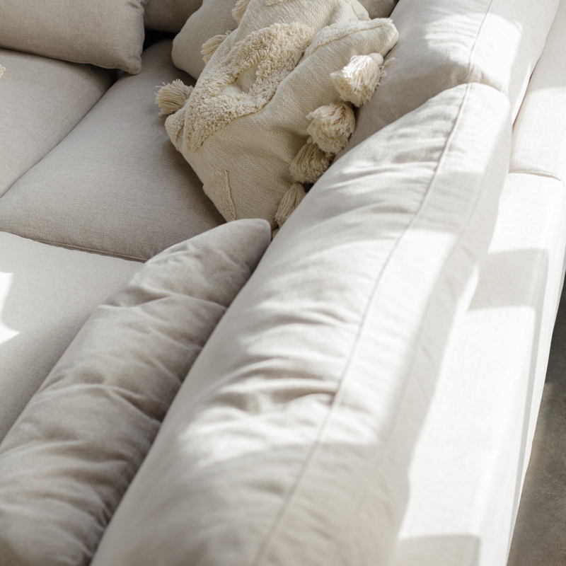 Canapé beige clair avec des coussins texturés à la lumière du soleil. Canape Paris by Atelier Bis