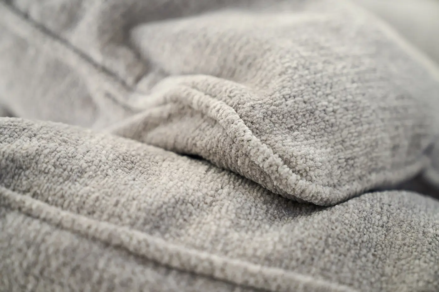 Gros plan sur un tissu molletonné gris clair, dont la texture et les plis sont visibles. Canape Paris by Atelier Bis