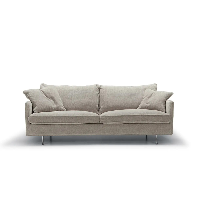 Causeuse en tissu gris clair avec deux coussins d'assise, quatre oreillers et de minces pieds en métal, sur fond blanc. Canape Paris by Atelier Bis