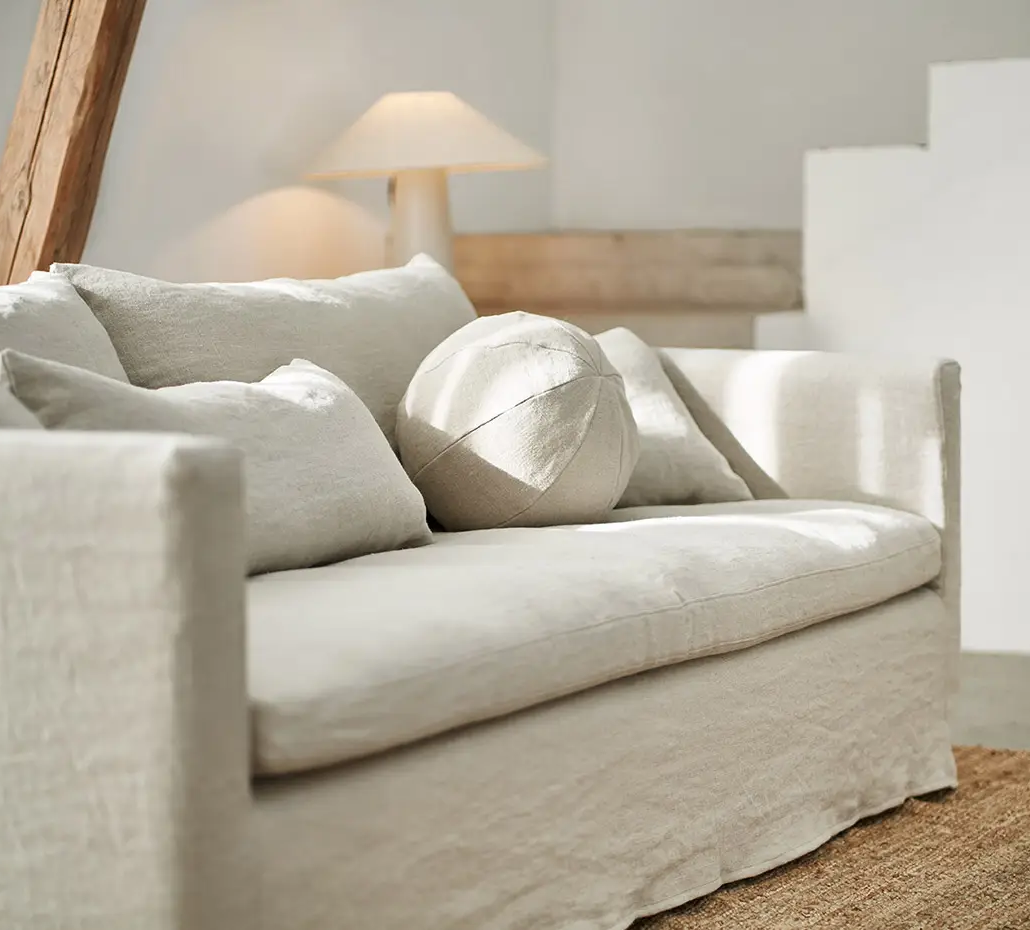 Canapé crème avec des coussins neutres dans un salon lumineux et minimaliste avec une lampe et un tapis. Canape Paris by Atelier Bis