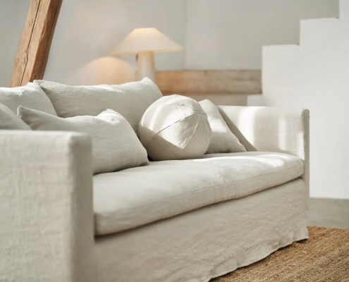 Canapé crème avec des coussins neutres dans un salon lumineux et minimaliste avec une lampe et un tapis. Canape Paris by Atelier Bis