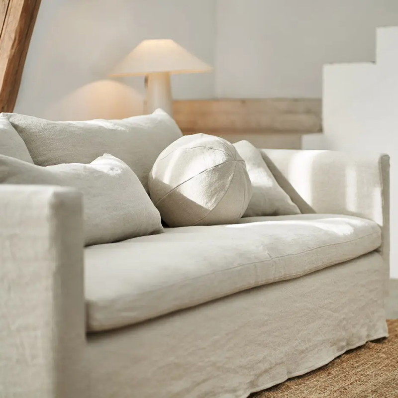 Canapé crème avec des coussins neutres dans un salon lumineux et minimaliste avec une lampe et un tapis. Canape Paris by Atelier Bis