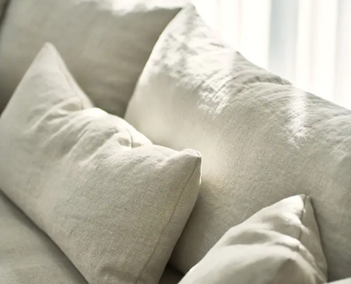 Gros plan d'un canapé beige avec des coussins assortis dans une douce lumière naturelle. Canape Paris by Atelier Bis