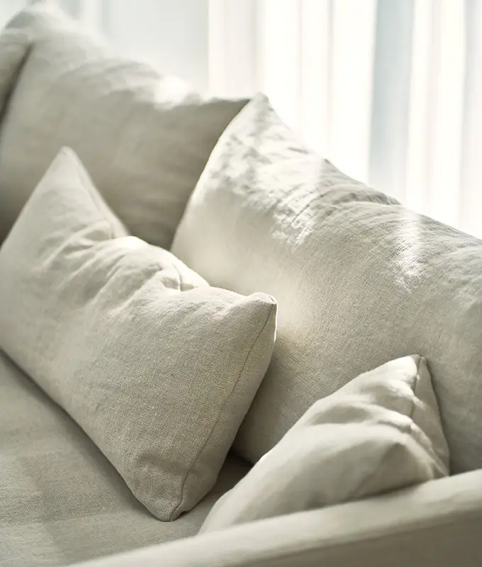 Gros plan d'un canapé beige avec des coussins assortis dans une douce lumière naturelle. Canape Paris by Atelier Bis