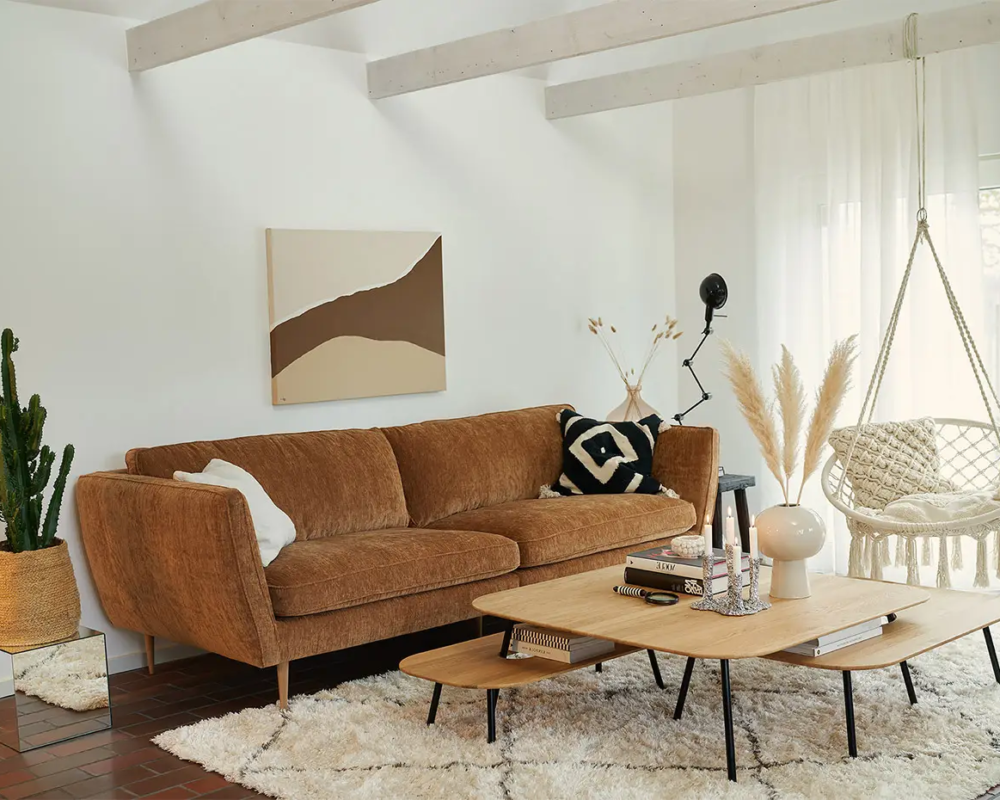 Salon moderne avec canapé marron, chaise suspendue, table basse, plantes décoratives et art mural abstrait. Canape Paris by Atelier Bis