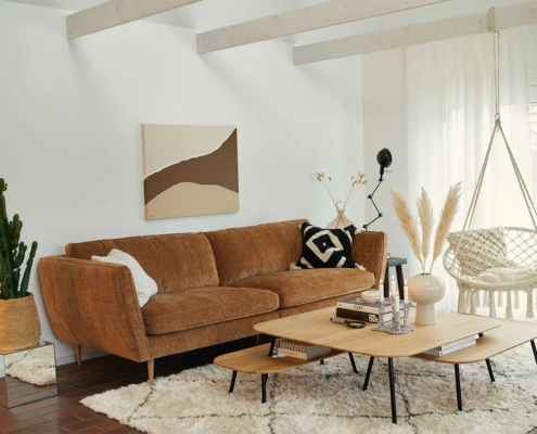 Salon moderne avec canapé marron, chaise suspendue, table basse, plantes décoratives et art mural abstrait. Canape Paris by Atelier Bis