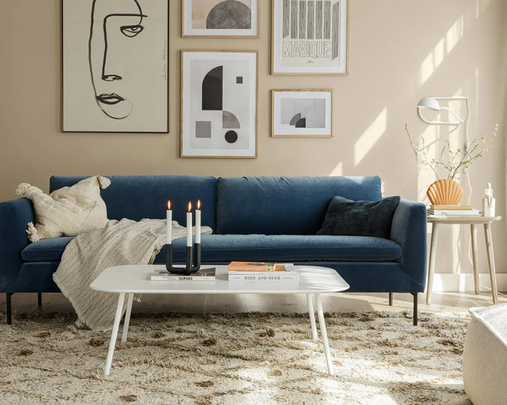Salon moderne avec canapé bleu, art mural abstrait, table basse blanche et décor neutre. Canape Paris by Atelier Bis