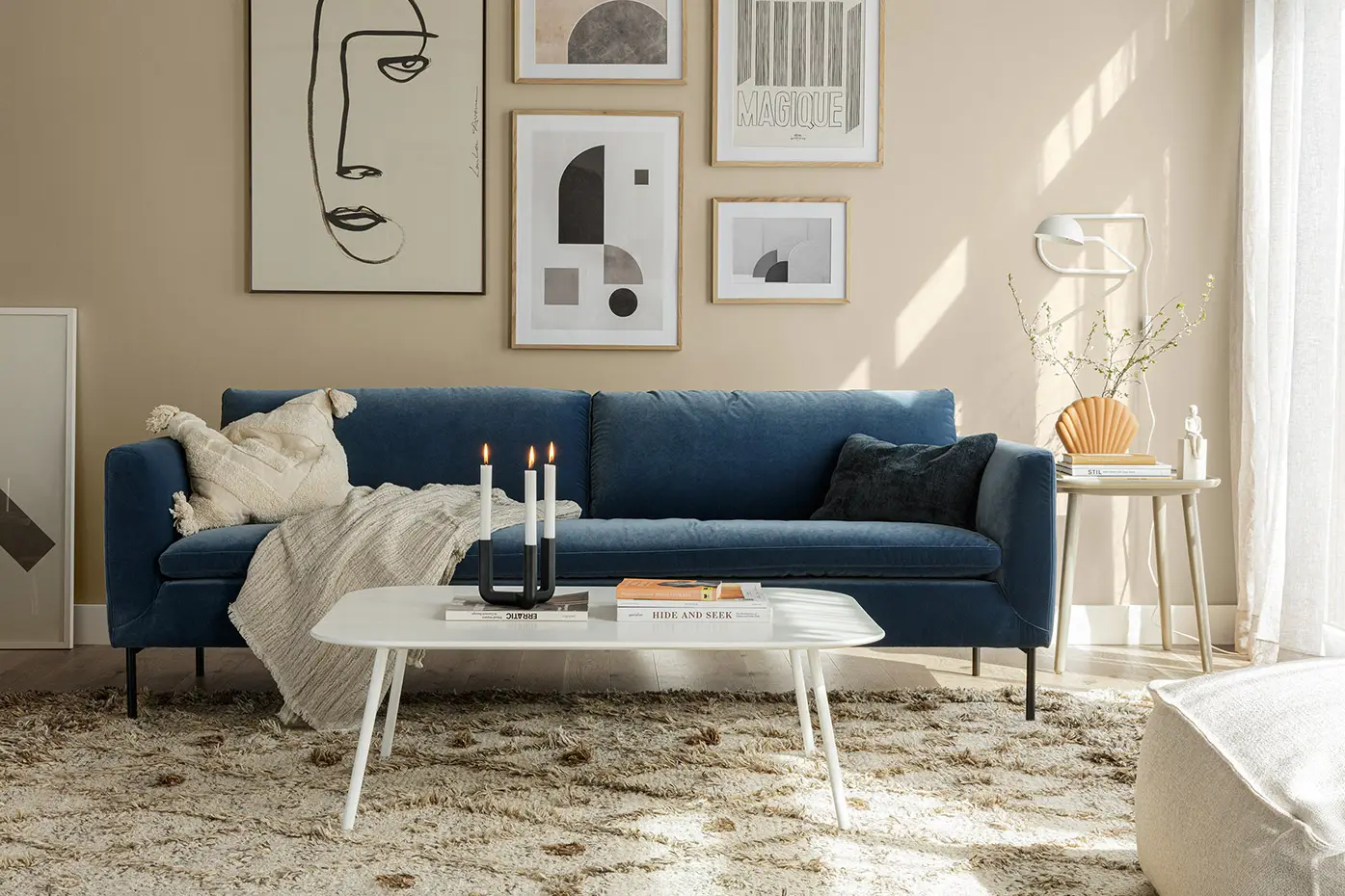 Salon moderne avec canapé bleu, art mural abstrait, table basse blanche et décor neutre. Canape Paris by Atelier Bis