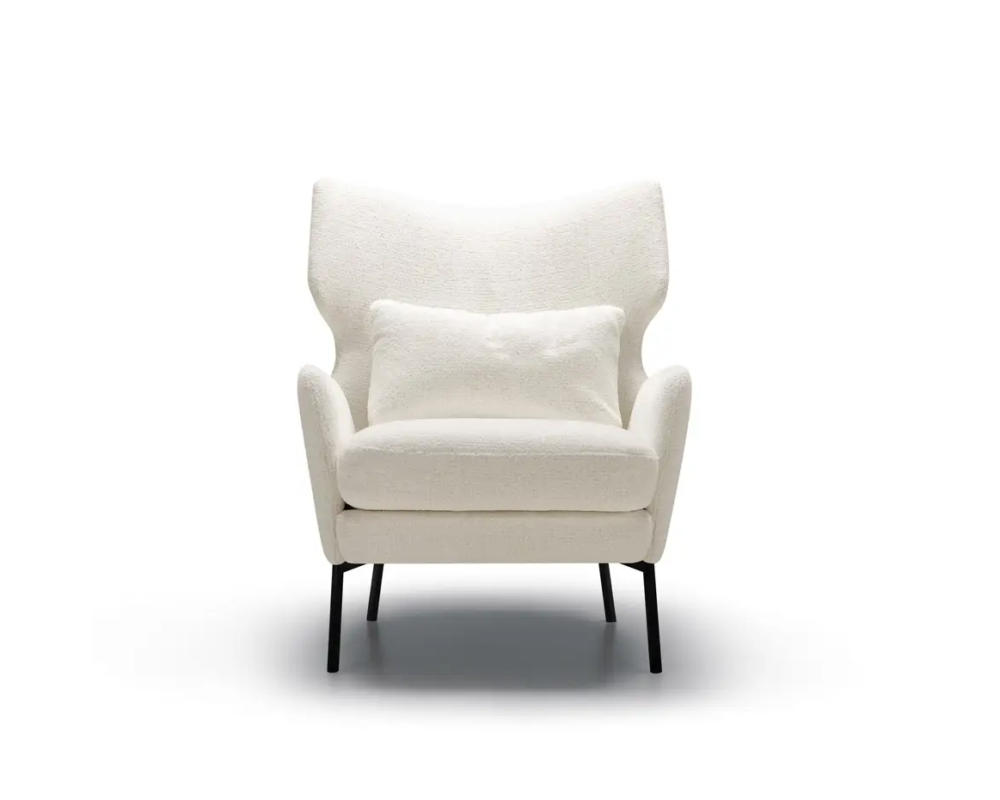 Fauteuil moderne blanc avec un coussin assorti, des pieds noirs et un dossier ailé, sur un fond uni. Canape Paris by Atelier Bis