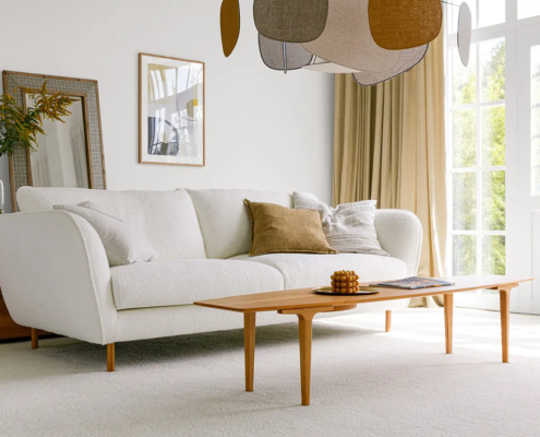 Salon lumineux avec un canapé blanc, une table basse en bois, une décoration moderne et de grandes fenêtres laissant entrer la lumière naturelle. Canape Paris by Atelier Bis