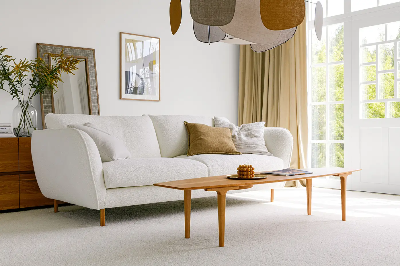 Salon lumineux avec un canapé blanc, une table basse en bois, une décoration moderne et de grandes fenêtres laissant entrer la lumière naturelle. Canape Paris by Atelier Bis