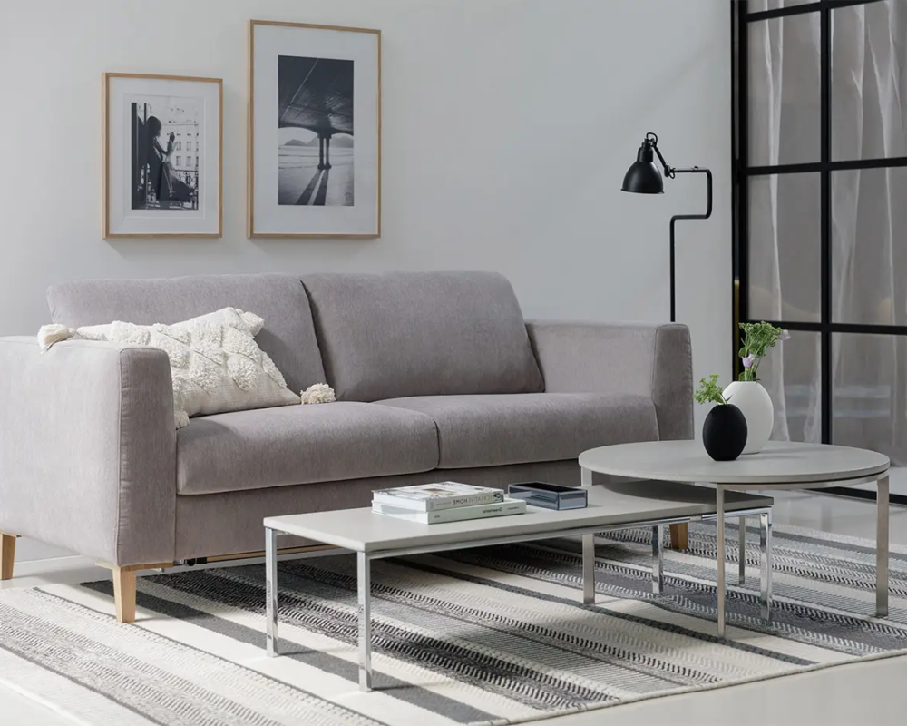 Salon moderne avec un canapé gris, des tables basses, des œuvres d'art murales encadrées et un lampadaire noir. Canape Paris by Atelier Bis