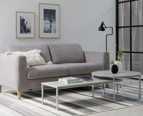 Salon moderne avec un canapé gris, des tables basses, des œuvres d'art murales encadrées et un lampadaire noir. Canape Paris by Atelier Bis