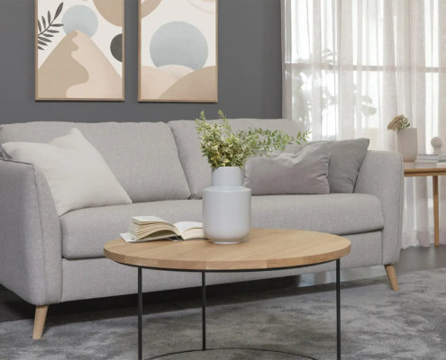 Salon moderne avec un canapé gris, une table basse ronde en bois et une décoration minimaliste. Canape Paris by Atelier Bis