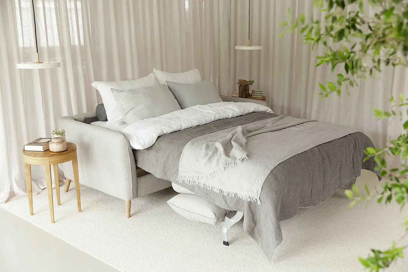 Canapé-lit moderne gris avec literie blanche et grise, tables d'appoint, plantes et lumière naturelle douce. Canape Paris by Atelier Bis