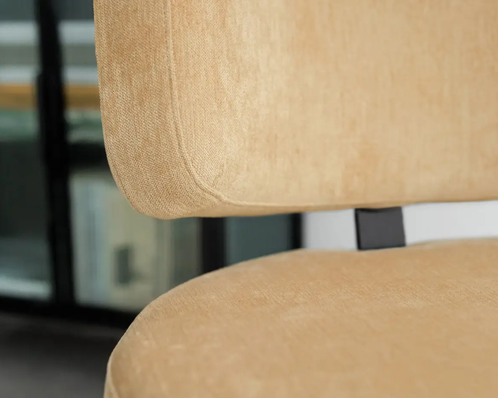 Gros plan d'une chaise beige rembourrée sur fond flou d'étagères. Canape Paris by Atelier Bis