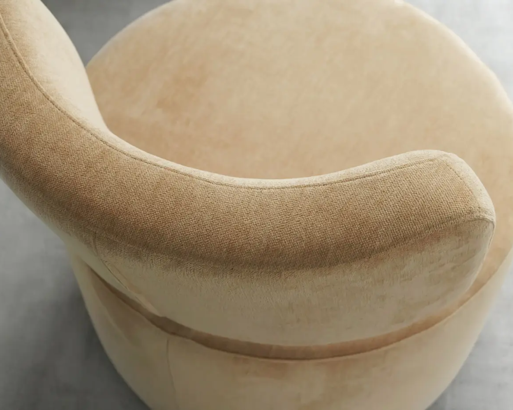 Fauteuil pivotant beige, rond, au dossier incurvé, vu de haut sur un sol gris. Canape Paris by Atelier Bis