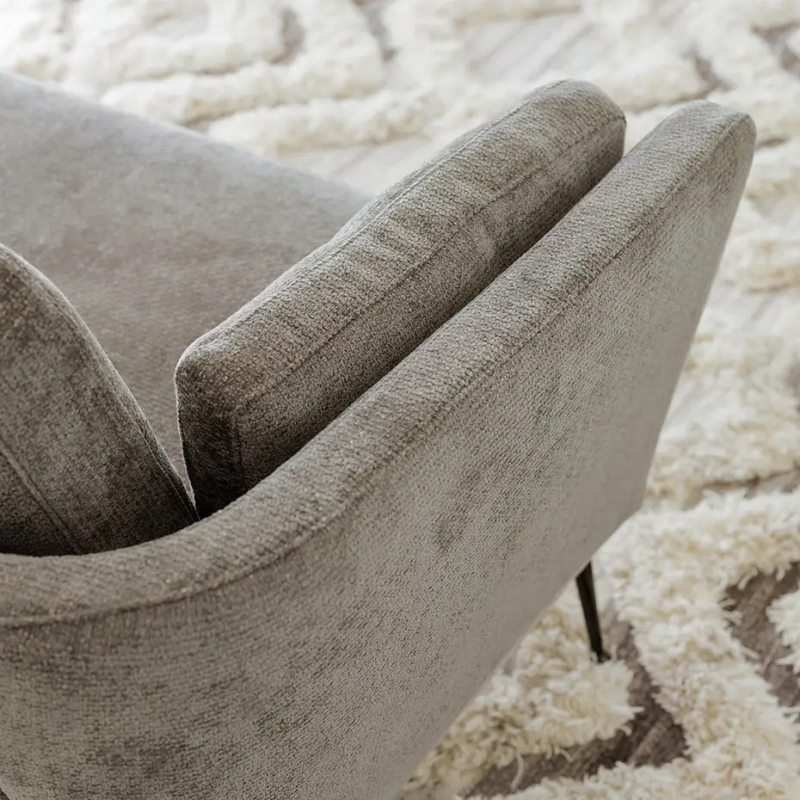 Fauteuil gris rembourré sur un tapis texturé crème et beige avec une petite plante sur une table d'appoint à proximité. Canape Paris by Atelier Bis