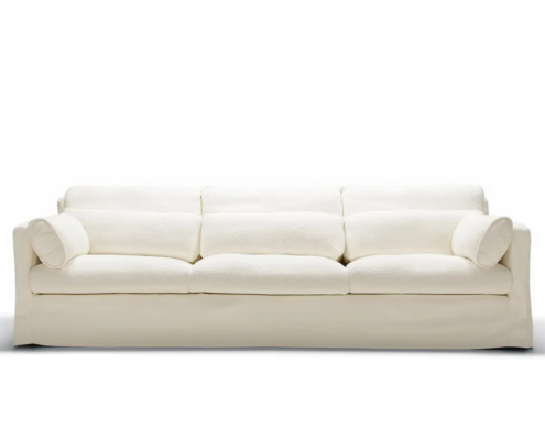 Canapé blanc à trois places avec des coussins en peluche et deux coussins cylindriques, sur fond blanc. Canape Paris by Atelier Bis