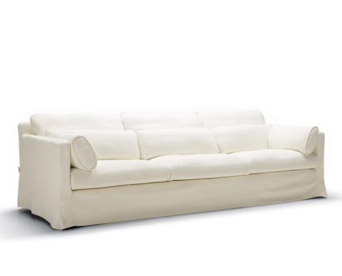 Canapé trois places capitonné blanc avec deux coussins cylindriques, présenté sur un fond blanc uni. Canape Paris by Atelier Bis