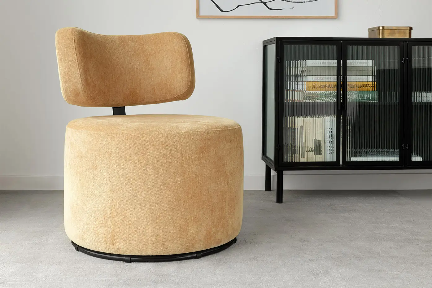 Un fauteuil pivotant moderne de couleur beige est posé sur un sol gris à côté d'un meuble en verre noir dans une pièce minimaliste. Canape Paris by Atelier Bis