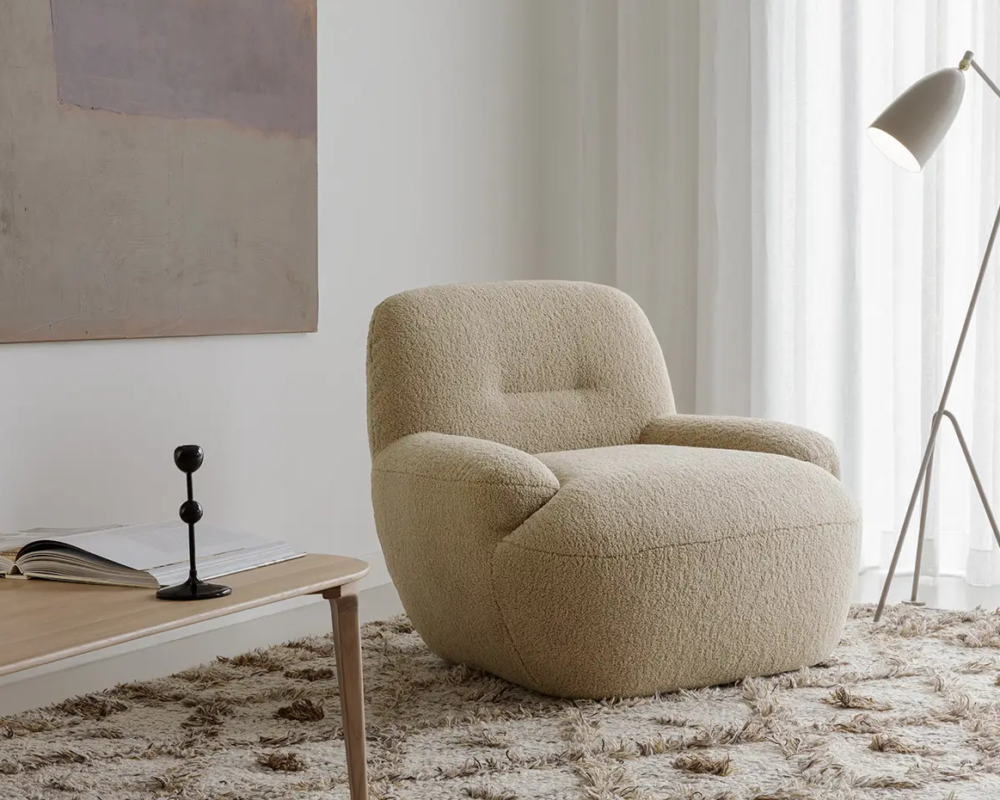 Fauteuil beige sur un tapis texturé à côté d'un lampadaire et d'une table basse dans une pièce à l'éclairage tamisé. Canape Paris by Atelier Bis