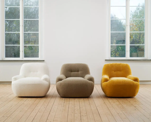 Trois fauteuils modernes - blanc, gris et jaune - sont posés côte à côte dans une pièce lumineuse au sol en bois. Canape Paris by Atelier Bis