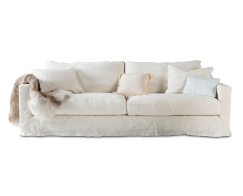 Canapé blanc avec quatre coussins et un jeté de fourrure drapé sur un bras, sur fond blanc. Canape Paris by Atelier Bis