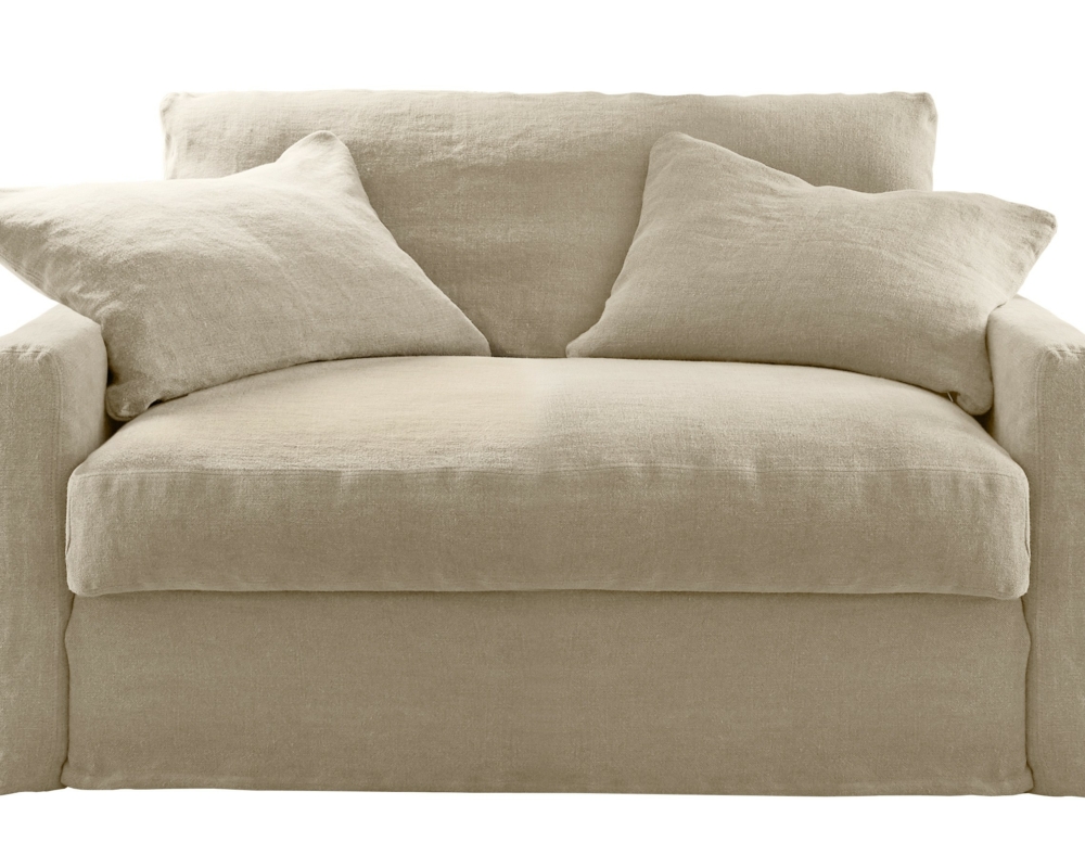 Un fauteuil tapissé beige avec des coussins moelleux et deux coussins assortis. Canape Paris by Atelier Bis