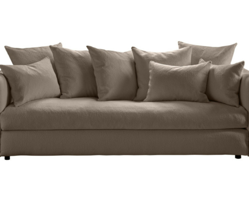 Un canapé beige en peluche avec sept coussins assortis, photographiés sur un fond blanc. Canape Paris by Atelier Bis