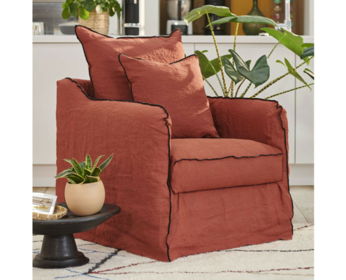 Un fauteuil couleur rouille avec deux coussins assortis à côté de plantes d'intérieur vertes dans un salon confortable. Canape Paris by Atelier Bis