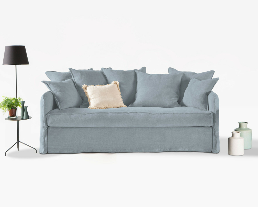 Canapé bleu clair convertible Homesprit Cassis avec coussins, à côté d'un lampadaire noir, d'une petite table et de trois vases décoratifs. Canape Paris by Atelier Bis