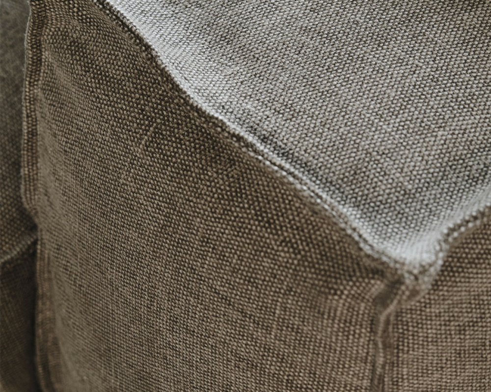 Gros plan sur un coussin de canapé en tissu gris texturé dont les coutures sont visibles. Canape Paris by Atelier Bis