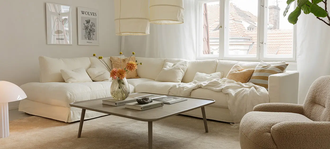 Salon lumineux avec un canapé blanc, un fauteuil beige, une table basse et de grandes fenêtres laissant entrer la lumière naturelle. Canape Paris by Atelier Bis