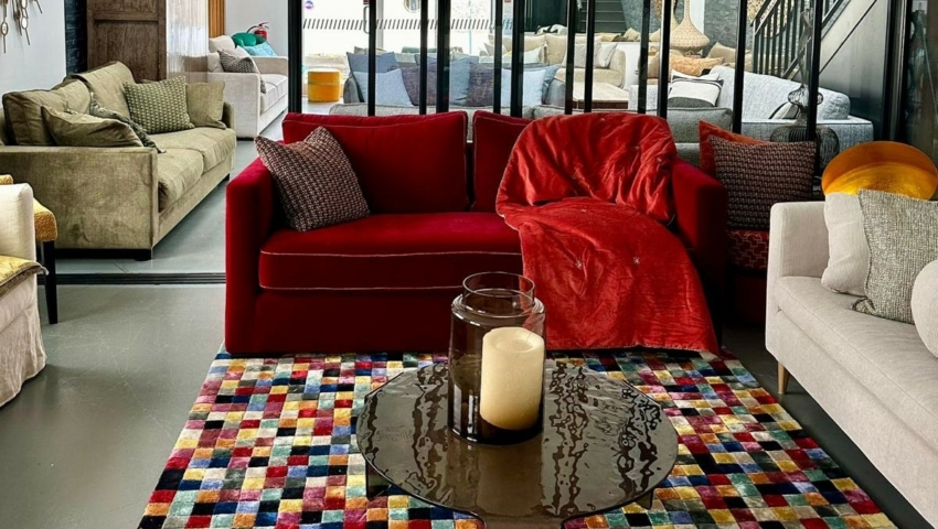 Salon moderne avec un canapé rouge, un tapis coloré, une table en verre et des canapés neutres, séparés par des portes en verre. Canape Paris by Atelier Bis