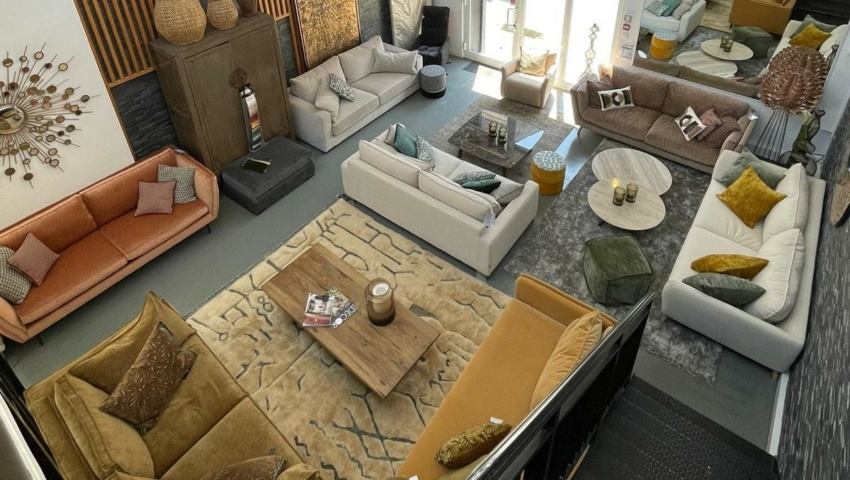 Salle d'exposition avec divers canapés, tables basses et décorations modernes, vue d'un escalier situé au-dessus. Canape Paris by Atelier Bis