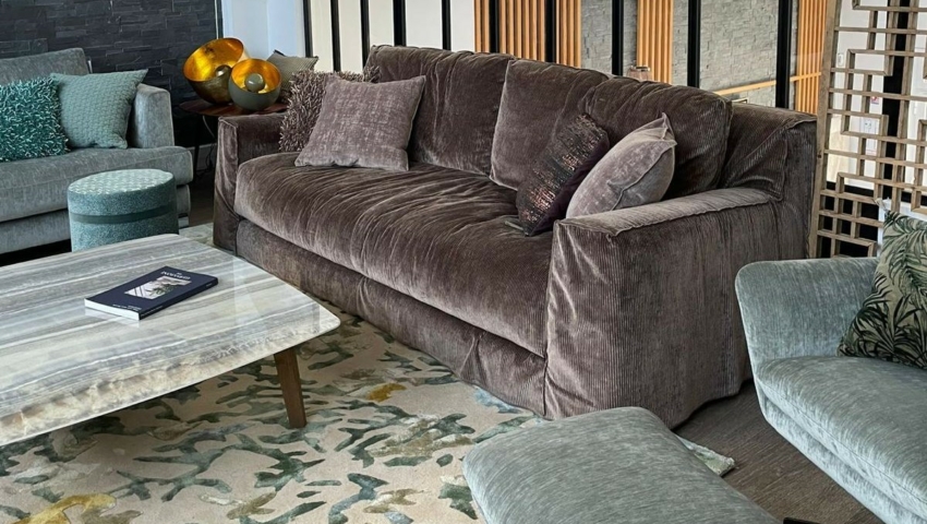 Salon moderne avec un canapé marron en peluche, des chaises sarcelles, une table basse en marbre et un tapis à motifs. Canape Paris by Atelier Bis