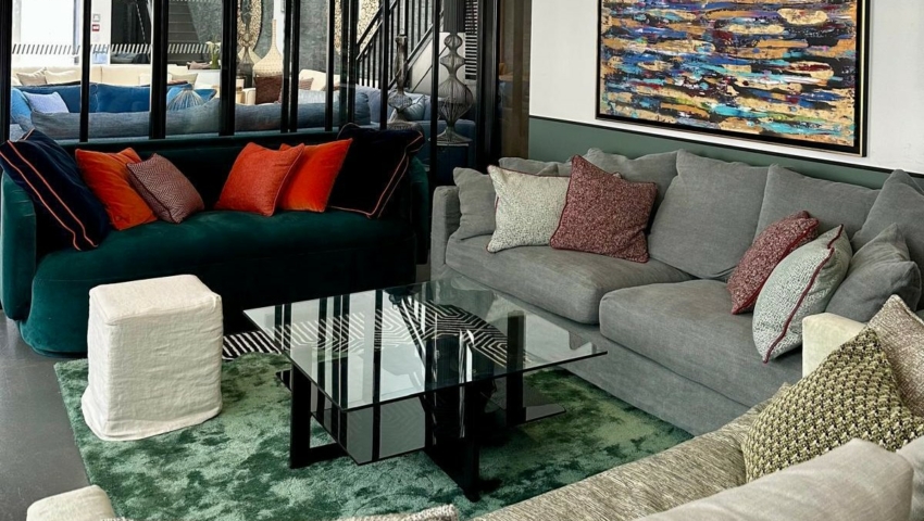 Salon moderne avec canapés colorés, table basse en verre, art mural abstrait et grande cloison vitrée. Canape Paris by Atelier Bis