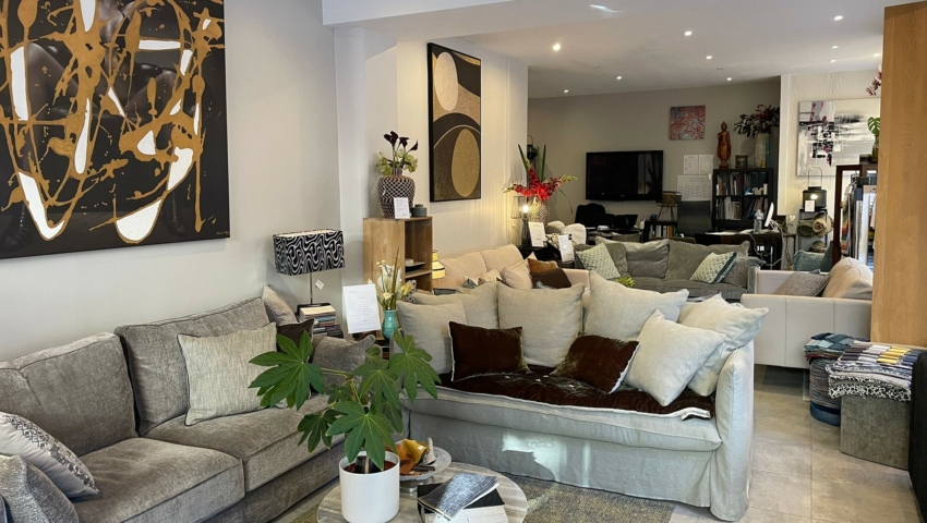 Salon moderne avec canapés gris, art abstrait, plantes d'intérieur et éclairage chaleureux. Canape Paris by Atelier Bis