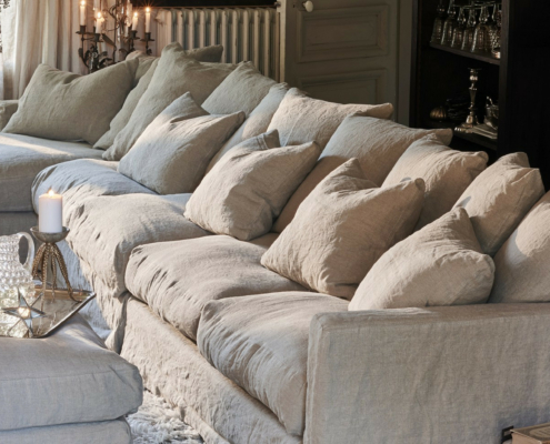 434 Le canapé beige Homesprit Biscarrosse déhoussable avec de nombreux coussins, un plateau éclairé à la bougie et un tapis moelleux créent un salon confortable et élégant. Canape Paris by Atelier Bis