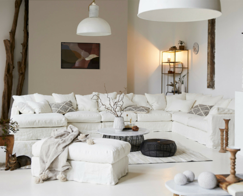 652 Salon lumineux avec un grand canapé Homesprit Biscarrosse déhoussable, une décoration moderne, des plantes, et un éclairage naturel doux. Canape Paris by Atelier Bis