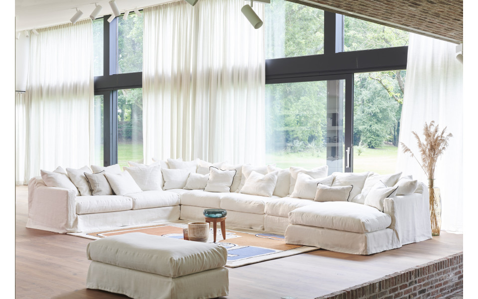 canape-3-places-biarritz-206-cm Salon spacieux avec un grand canapé Homesprit Biscarrosse déhoussable, un ottoman et des fenêtres allant du sol au plafond avec des rideaux diaphanes. Canape Paris by Atelier Bis